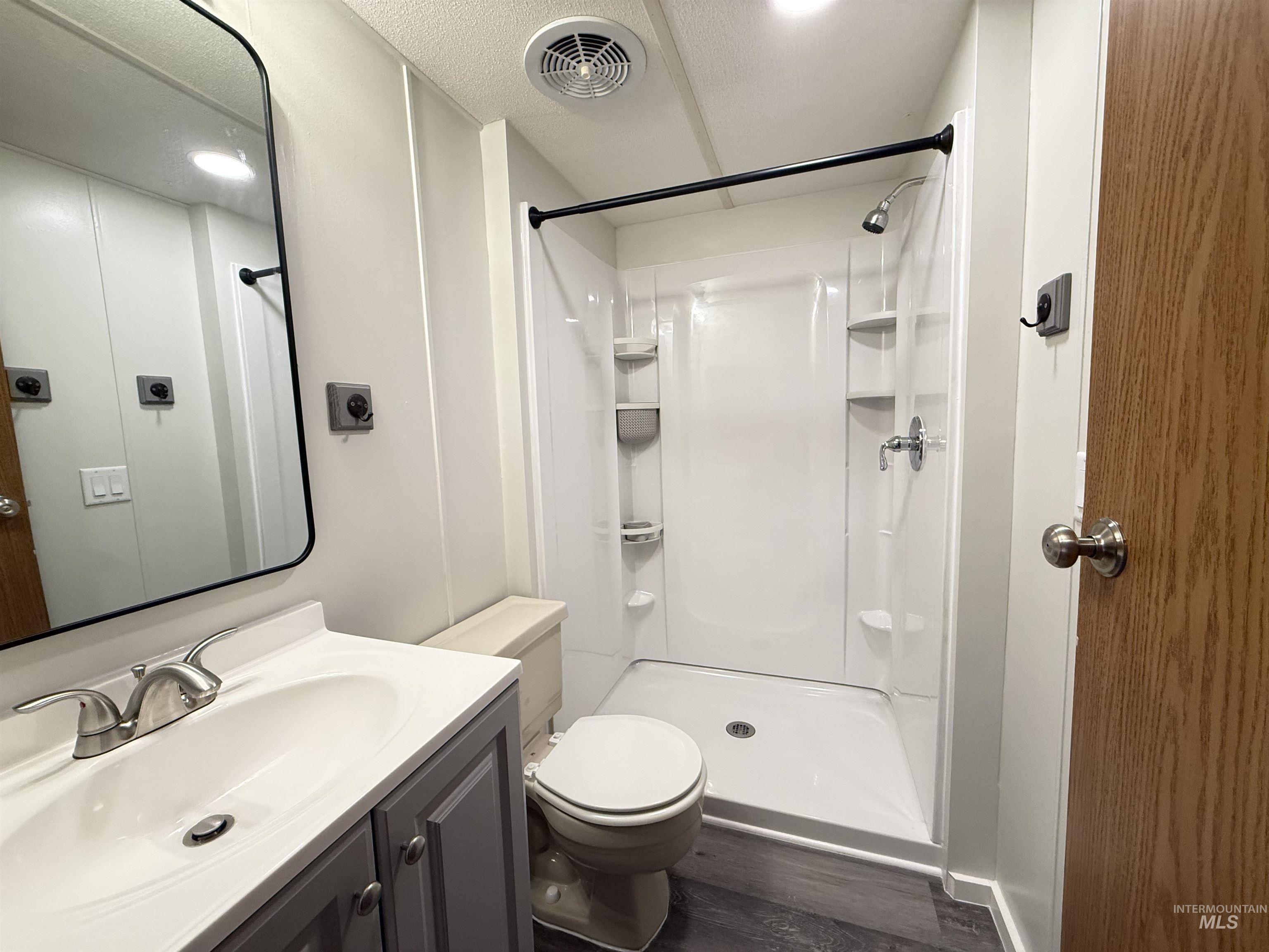 2015 6th Avenue, Unit 321 Clarkston, WA 99403 - Photo 18 of 34 Bathroom with vanity, a stall shower, dark wood-type flooring, and a textured ceiling