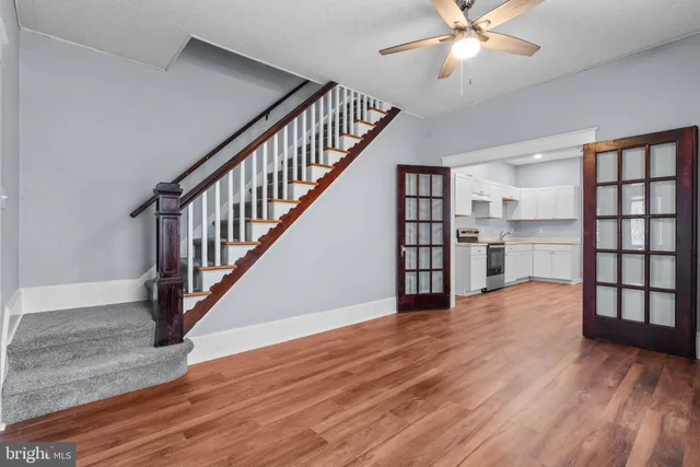 a view of empty room with wooden floor and fan