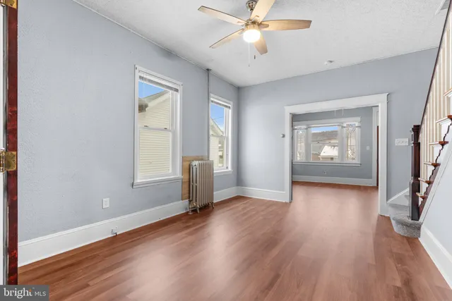 an empty room with wooden floor fan and windows