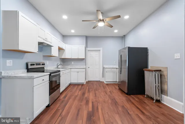 a kitchen with stainless steel appliances a refrigerator a sink dishwasher a stove and white cabinets with wooden floor