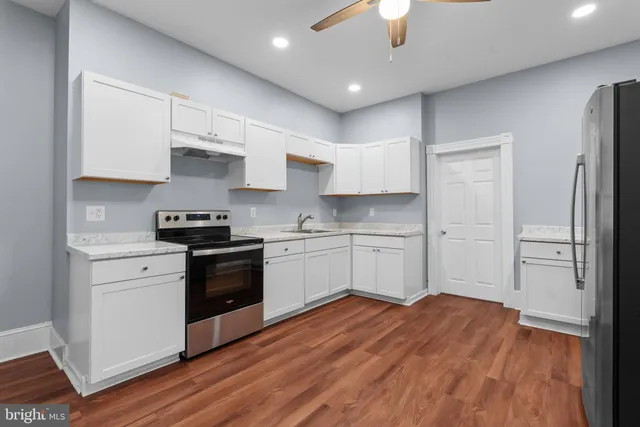 a kitchen with stainless steel appliances a sink cabinets and wooden floor