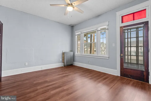 a view of an empty room with wooden floor and a window