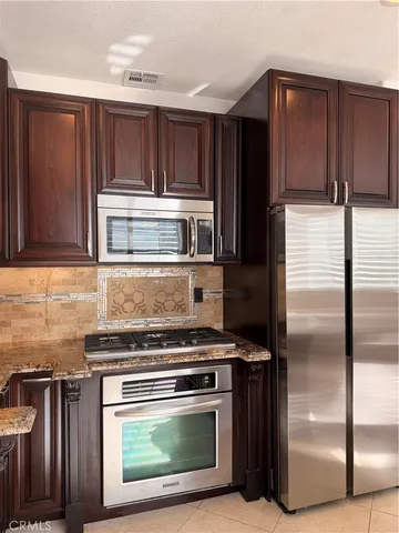 a kitchen with stainless steel appliances kitchen island granite countertop a sink counter space and a view of living room