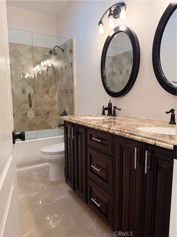 a bathroom with a granite countertop sink toilet and a mirror
