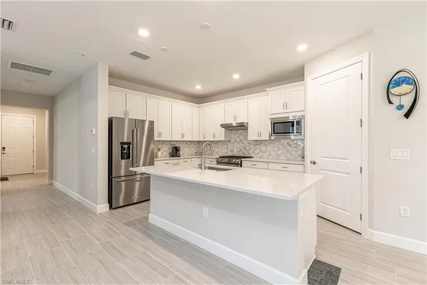 a large kitchen with stainless steel appliances a refrigerator sink and cabinets
