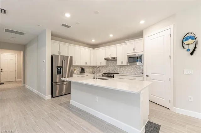 a large kitchen with stainless steel appliances a refrigerator sink and cabinets
