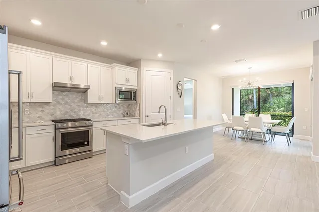 a large white kitchen with stainless steel appliances granite countertop a stove and a sink with granite countertops