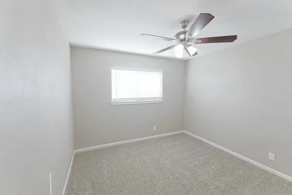 an empty room with a window and a fan