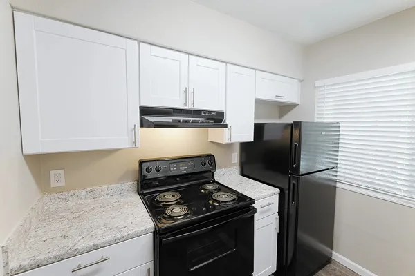 a kitchen with stainless steel appliances granite countertop white cabinets and a stove