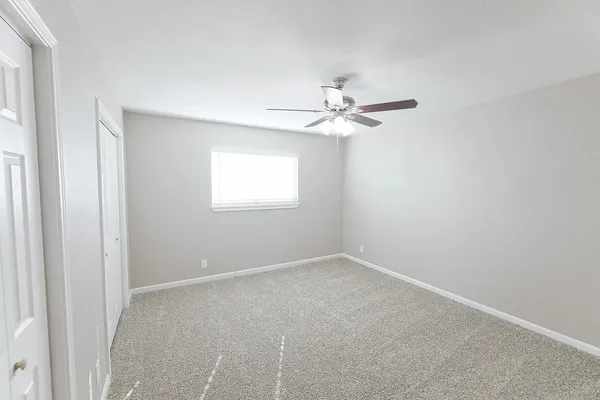 an empty room with a window and a fan