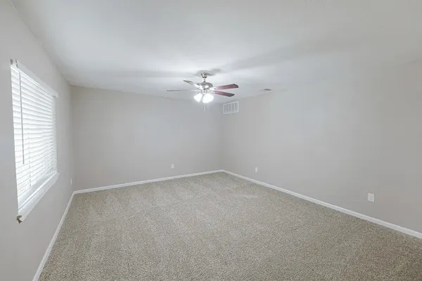 an empty room with a window and a chandelier fan