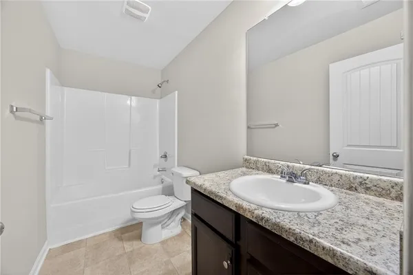 a bathroom with a granite countertop sink a toilet and shower