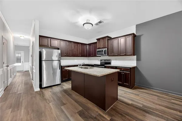 a kitchen with stainless steel appliances granite countertop a refrigerator stove and wooden floor