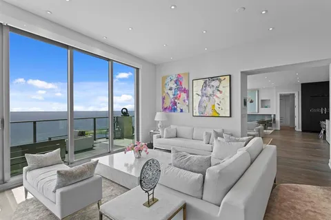 a view of a dining room and livingroom with furniture wooden floor a rug a flat screen tv a rug and a large window