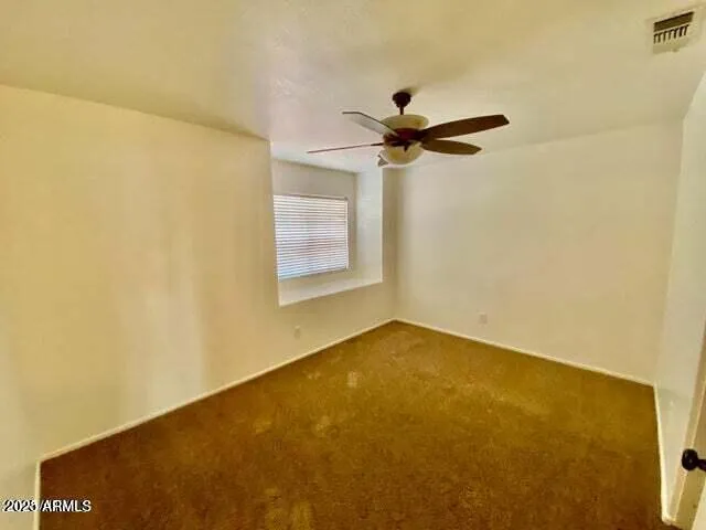 an empty room with a window and a ceiling fan