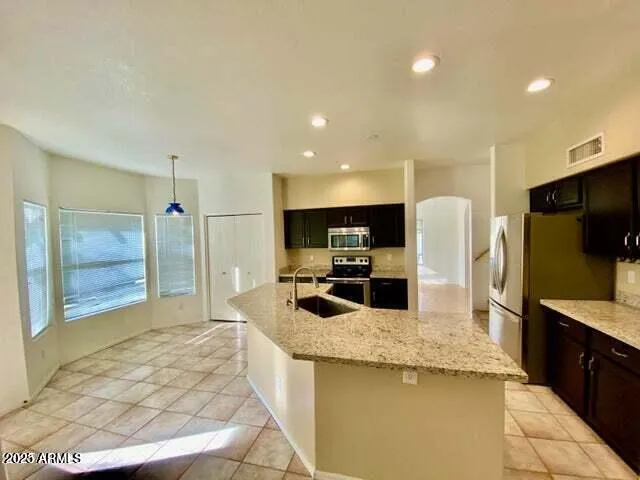 a kitchen with stainless steel appliances kitchen island granite countertop a refrigerator and a sink