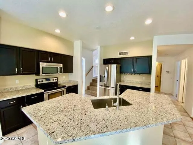 a kitchen with stainless steel appliances kitchen island granite countertop a stove and a sink