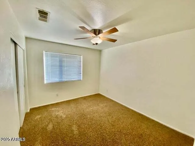 an empty room with a ceiling fan and a window