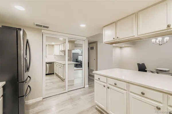 a kitchen with a refrigerator and white cabinets