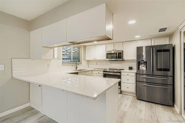 a kitchen with stainless steel appliances a refrigerator and a stove top oven