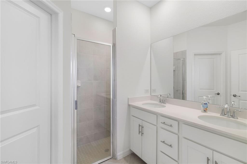 2052 Vermont Lane Naples, FL 34120 - Photo 15 of 35 a bathroom with a shower sink and mirror