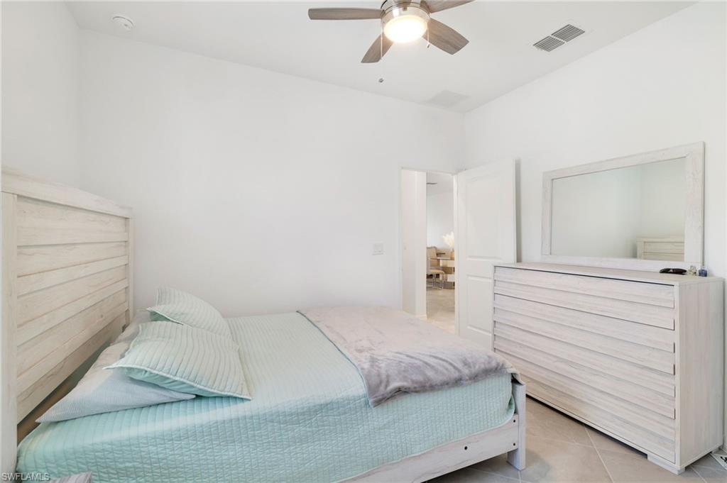 2052 Vermont Lane Naples, FL 34120 - Photo 16 of 35 a bedroom with a large bed and chandelier