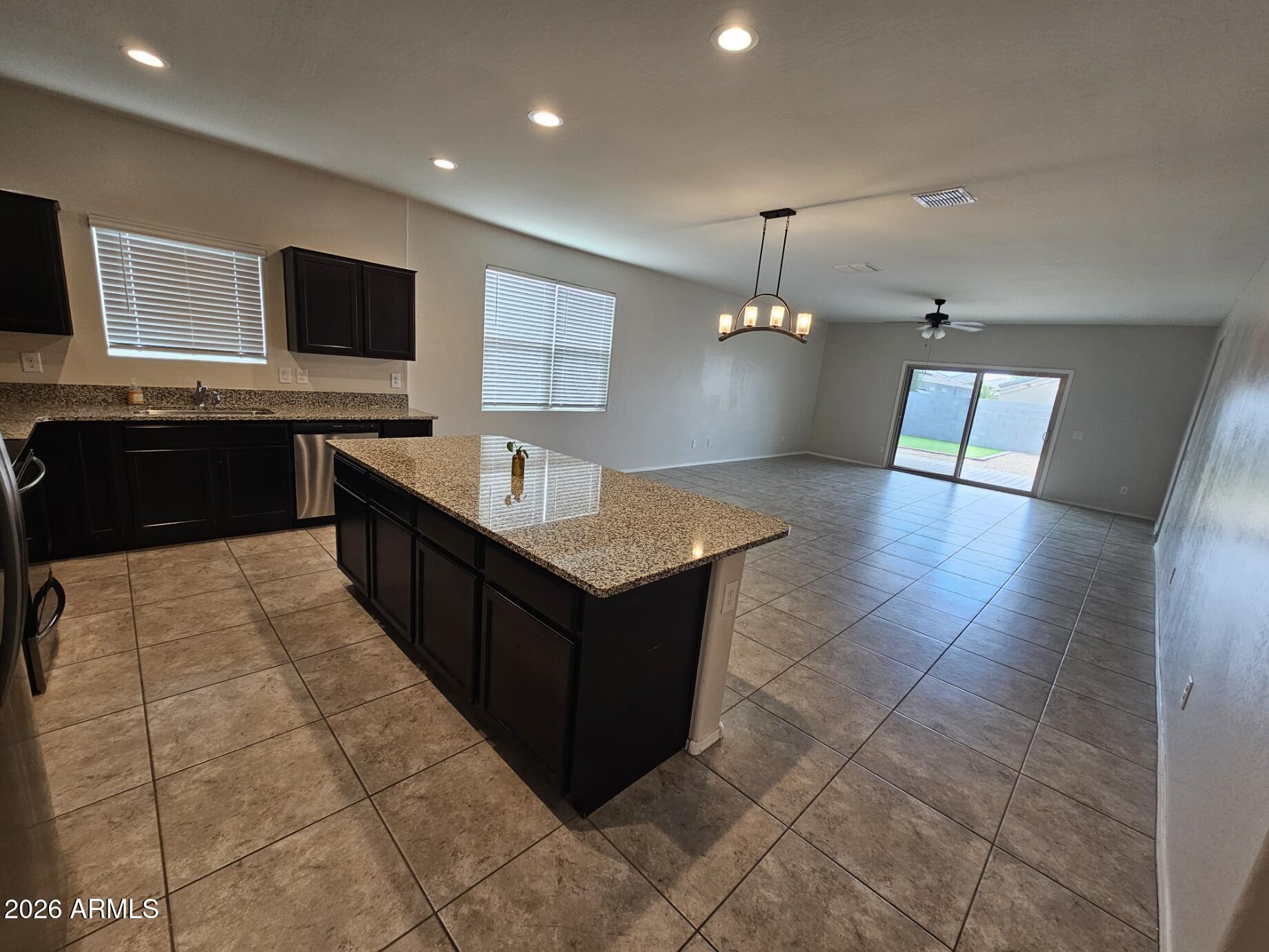 25573 West Coles Road Buckeye, AZ 85326 - Photo 4 of 12 a large kitchen with stainless steel appliances a large counter top a stove a chimney a sink and a refrigerator