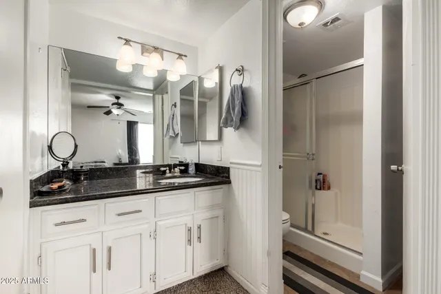 a bathroom with a granite countertop sink a mirror and shower