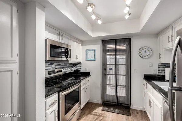 a kitchen with stainless steel appliances granite countertop a stove top oven a sink and a refrigerator