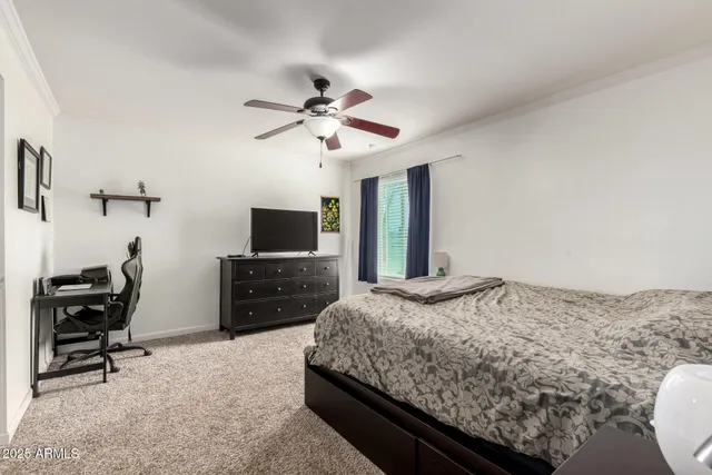 a bedroom with a bed a computer on a desk and chair