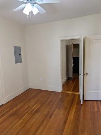 an empty room with wooden floor and chandelier fan