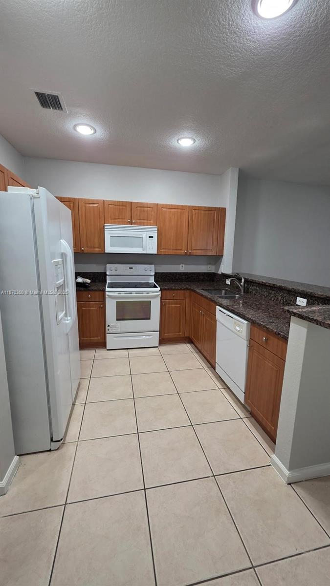 2748 Southwest 83rd Avenue, Unit 108 Miramar, FL 33025 - Photo 5 of 20 a kitchen with stainless steel appliances granite countertop a stove a sink and a refrigerator
