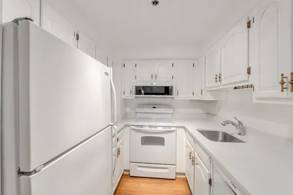 a view of a kitchen with white cabinets and white appliances