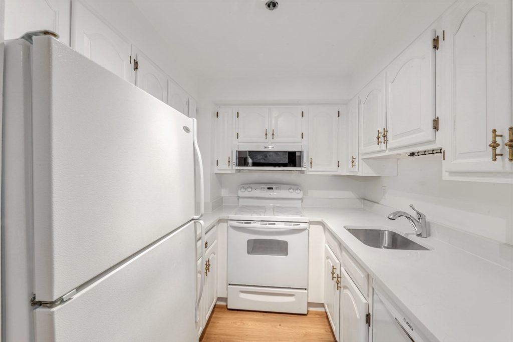 a view of a kitchen with white cabinets and white appliances