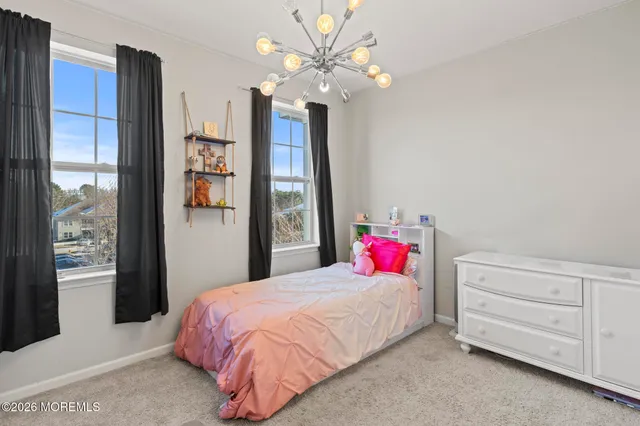 a bedroom with a bed dresser and a chandelier