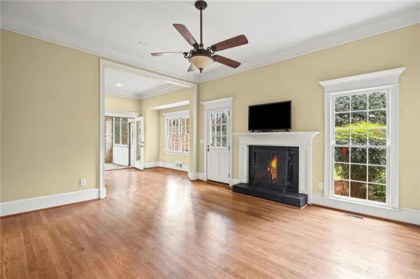 a view of a livingroom with a fireplace a ceiling fan and wooden floor