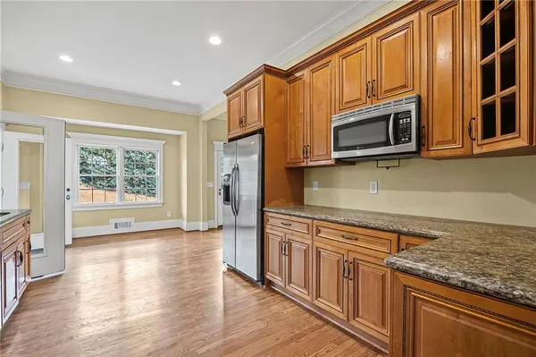 a kitchen with stainless steel appliances granite countertop a refrigerator a stove top oven and a sink with cabinets