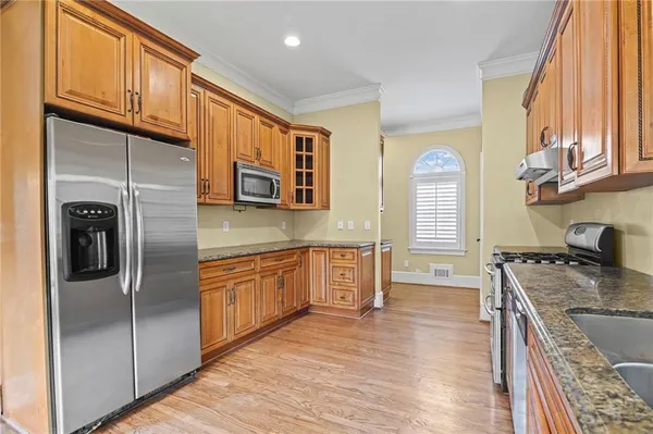 a kitchen with stainless steel appliances granite countertop a refrigerator a stove and a sink with wooden floor