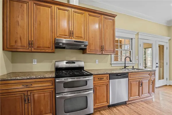 a kitchen with granite countertop wooden cabinets and a stove top oven