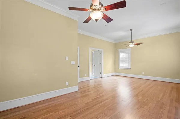an empty room with wooden floor ceiling fan and window