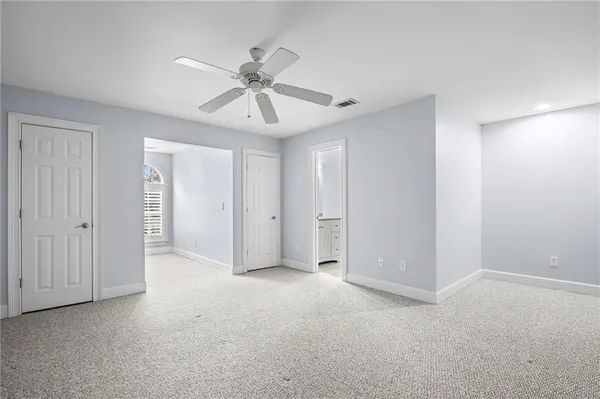 a view of an empty room and chandelier fan