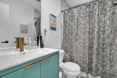 a bathroom with a granite countertop sink and a toilet