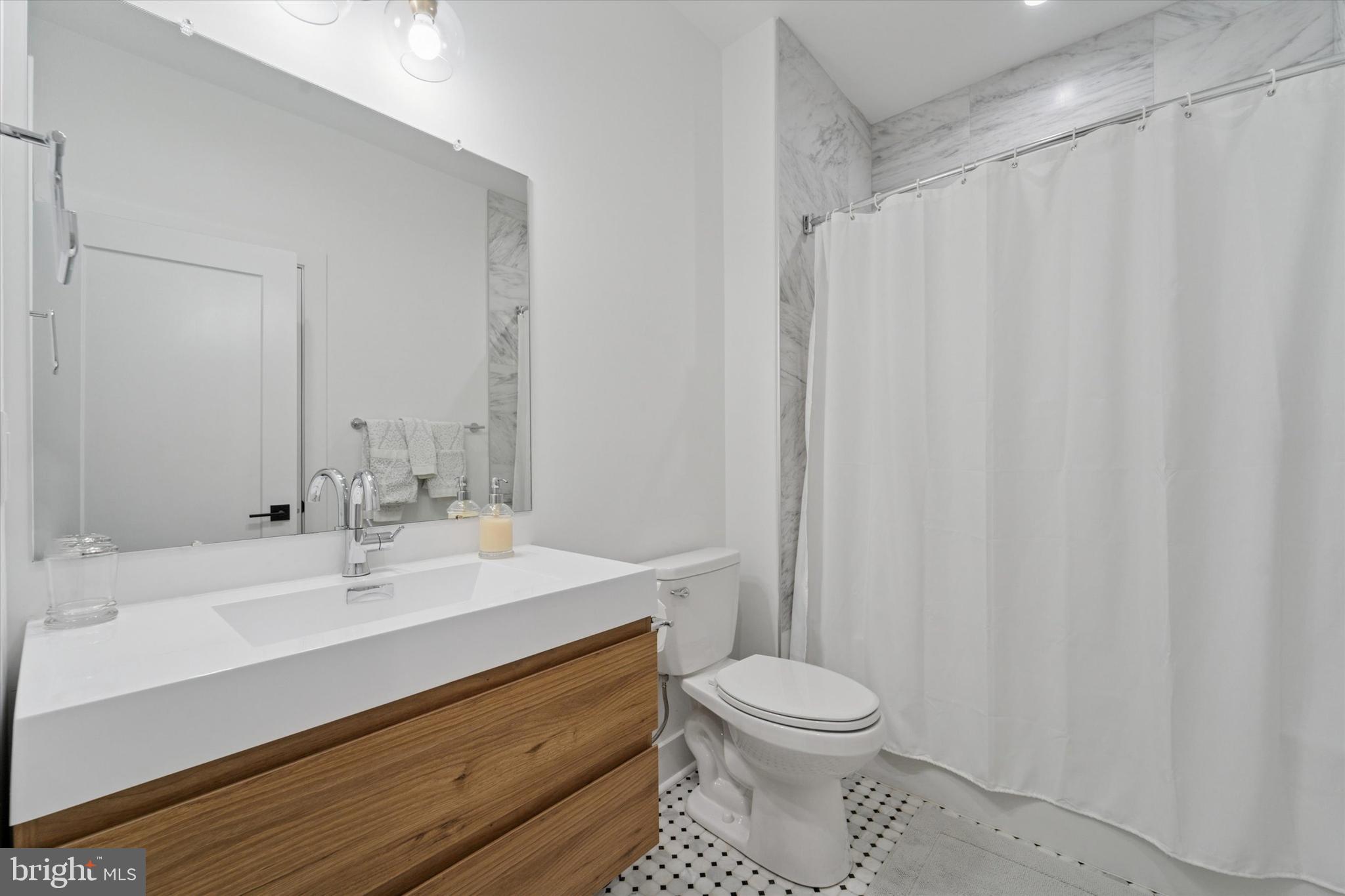 73 East Sharpnack Street Philadelphia, PA 19119 - Photo 32 of 50 a bathroom with a sink a toilet and shower curtain