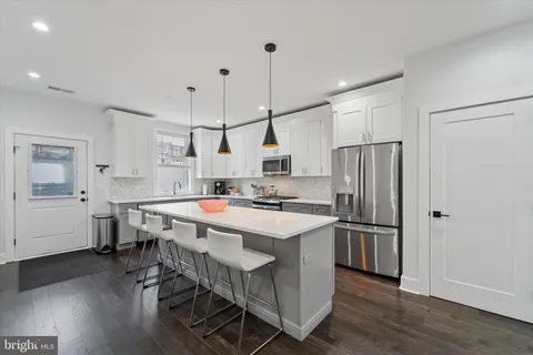 a kitchen with stainless steel appliances granite countertop a sink a stove a refrigerator and island with wooden floor