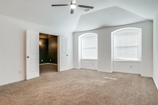 an empty room with windows and fan