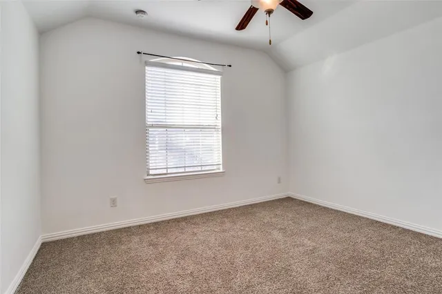 an empty room with ceiling fan and window