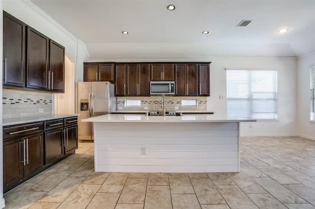 a kitchen with stainless steel appliances granite countertop a stove a sink and a microwave