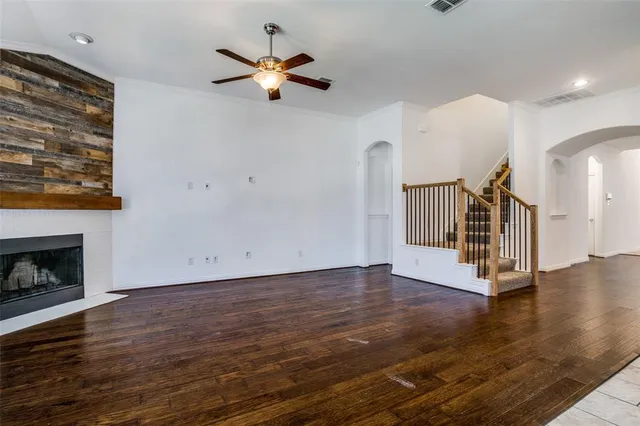 a view of an empty room with wooden floor a fireplace and a window