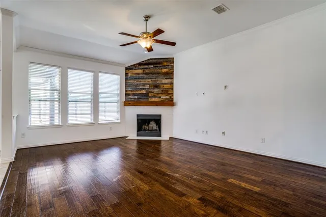 an empty room with wooden floor chandelier and windows