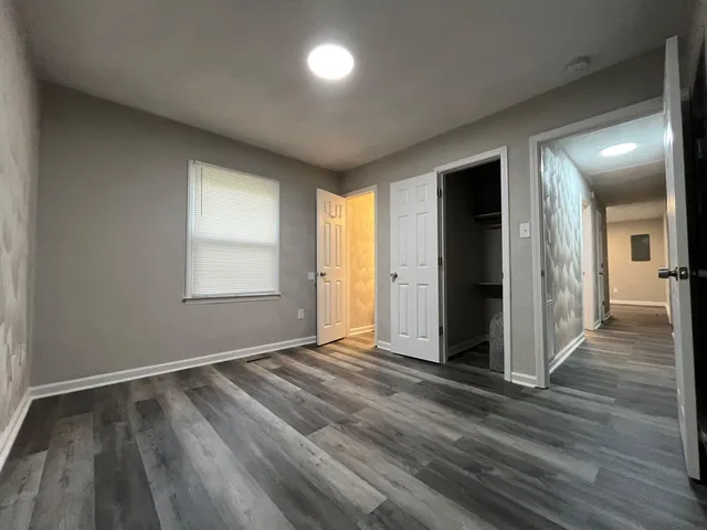 an empty room with wooden floor and windows